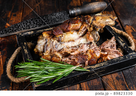 Roasted pork knuckle eisbein meat in a wooden tray with knife. Dark wooden background. Top view Roasted pork knuckle eisbein meat in a wooden tray with knife. Dark wooden background. Top view 89823330