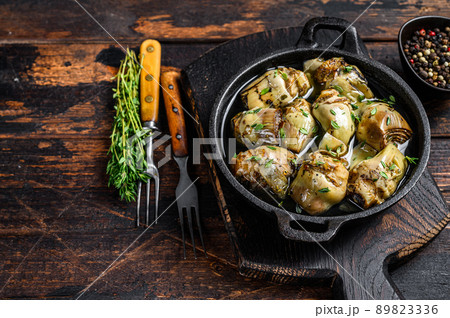 Marinated artichokes in olive oil in a pan. Dark wooden background. Top view. Copy space Marinated artichokes in olive oil in a pan. Dark wooden background. Top view. Copy space 89823336
