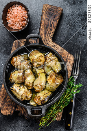 Canned artichokes in olive oil on a rustic wooden kitchen table. Black background. Top view Canned artichokes in olive oil on a rustic wooden kitchen table. Black background. Top view 89823339