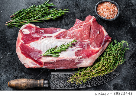 Fresh Raw lamb mutton shoulder meat with butcher knife. Black background. Top view 89823443