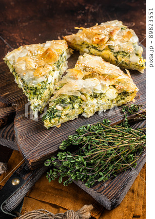 Spanakopita Greek Pie with Spinach and Cheese on wooden board. Dark background. Top view 89823551