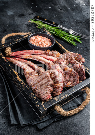 Grilled lamb chop steak, mutton meat cutlet in wooden tray. Black background. Top view Grilled lamb chop steak, mutton meat cutlet in wooden tray. Black background. Top view 89823787