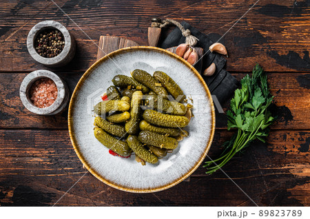Plate with Pickled gherkins cucumbers on wooden board. Wooden background. Top view 89823789
