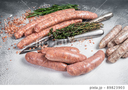 Raw Sausages variation - Beef, pork, lamb and chicken meat on a butcher table with rosemary and thyme. White background. Top view 89823903