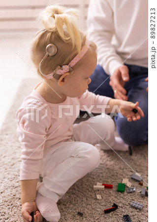 Happy child girl with cochlear implant having fun with her father - hearing aid for deaf and innovative health technology and diversity concept Happy child girl with cochlear implant having fun with her father - hearing aid for deaf and innovative health technology and diversity concept 89827213