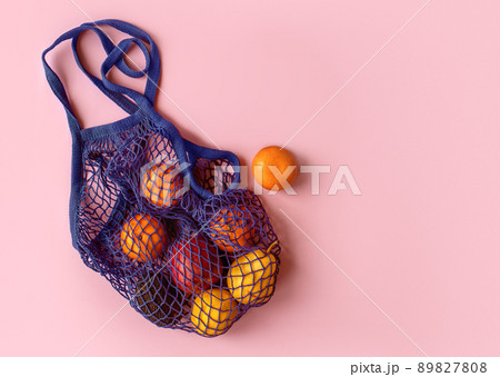 Net bag with fruit on bright background. Zero waste and ecology conservation concept. Fresh apples, tangerines, avocado and pomegranate in a reusable eco friendly shopping bag 89827808