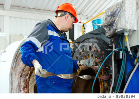 Engineer in helmet inspects and repairs gas equipment of boiler room. Cleaning and maintenance of Engineer in helmet inspects and repairs gas equipment of boiler room. Cleaning and maintenance of 89828394