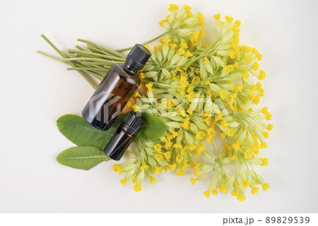 Dark glass bottles on cowslip, Primula veris, flowers, top view. 89829539