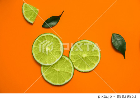 Flat lay composition with slices of fresh juicy lime on orange background 89829853
