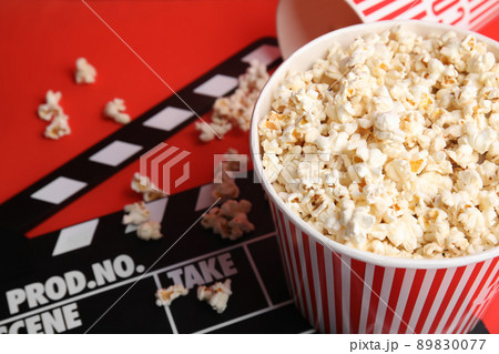 Tasty pop corn and clapboard on red background 89830077
