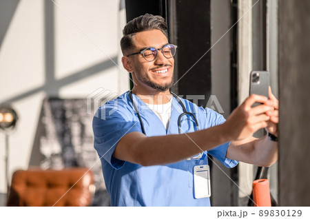Physician with a radiant smile taking photos of himself 89830129