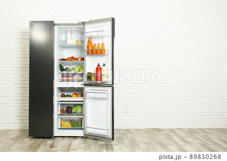 Open refrigerator filled with food near white brick wall, space for text Open refrigerator filled with food near white brick wall, space for text 89830268