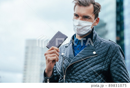 young man in a protective mask showing his passport 89831075