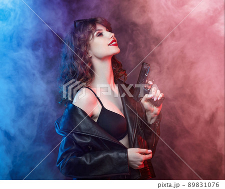 beautiful young Caucasian girl with bright red lips poses with a gun. beautiful young Caucasian girl with bright red lips poses with a gun. 89831076