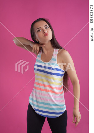 Brunette woman with long hair, dressed in colorful striped shirt, posing against pink studio background. Sincere emotions. Close-up. Brunette woman with long hair, dressed in colorful striped shirt, posing against pink studio background. Sincere emotions. Close-up. 89833373