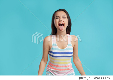 Brunette woman with long hair, dressed in colorful striped shirt, posing against blue studio background. Sincere emotions. Close-up. Brunette woman with long hair, dressed in colorful striped shirt, posing against blue studio background. Sincere emotions. Close-up. 89833475