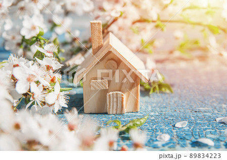 Springtime greeting card and miniature wooden house and copy space. Blooming spring trees close up. 89834223