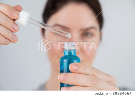 Caucasian woman uses blue anti-wrinkle face serum. 89834664