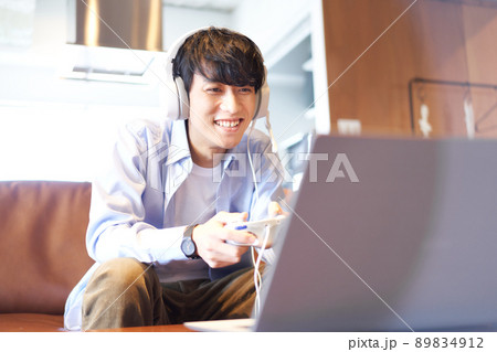 ソファに座ってゲームを楽しむ若い男性 89834912