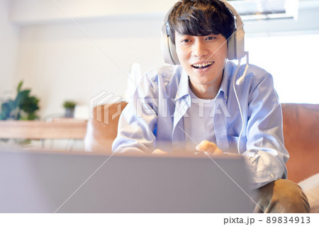 ソファに座ってゲームを楽しむ若い男性 89834913