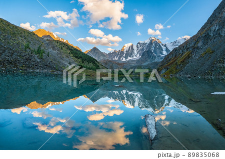 Morning mountain landscape with a large lake in the caldera. Calm azure mountain lake with the reflection of snow-capped mountain peaks in the water. 89835068