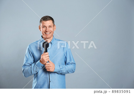 Male journalist with microphone on grey background. Space for text Male journalist with microphone on grey background. Space for text 89835091