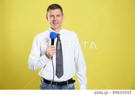 Male journalist with microphone on yellow background Male journalist with microphone on yellow background 89835092