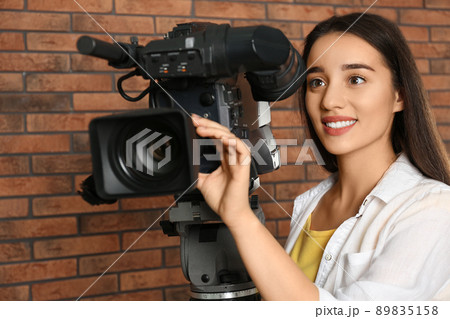 Operator with professional video camera near brick wall Operator with professional video camera near brick wall 89835158