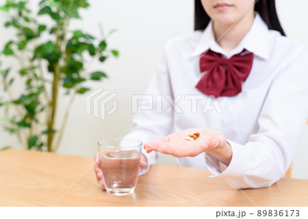 コップの水で薬を飲む女子高校生　コップの水と薬、錠剤、サプリ　 89836173