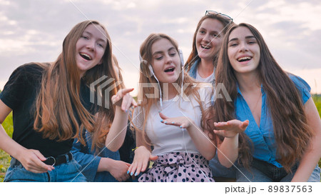 A group of girls of friends are listening to music on headphones and dancing to a friend. A group of girls of friends are listening to music on headphones and dancing to a friend. 89837563