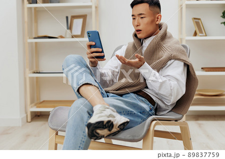 Asian man home with smartphone in chair interior internet Lifestyle Asian man home with smartphone in chair interior internet Lifestyle 89837759