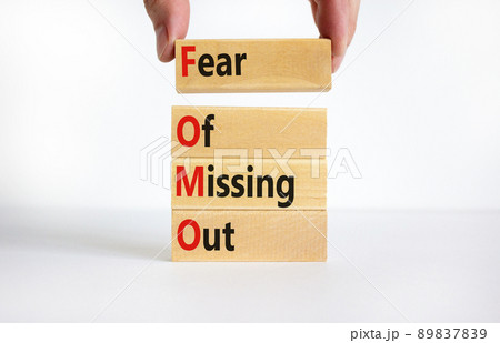 FOMO fear of missing out symbol. Concept words FOMO fear of missing out on wooden blocks on a beautiful white background. Businessman hand. Business FOMO fear of missing out concept. Copy space. 89837839