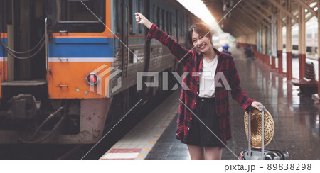 Happy Young traveler woman looking for friend planning trip at train station. Summer and travel lifestyle concept. Happy Young traveler woman looking for friend planning trip at train station. Summer and travel lifestyle concept. 89838298