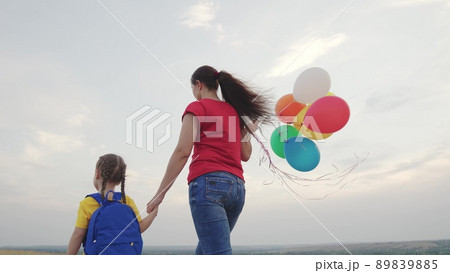 mother holds little child daughter with backpack against sky. happy family life. mom with kid girl walks along rural road park. teamwork. family adventures. travel naturechild hand parent mother holds little child daughter with backpack against sky. happy family life. mom with kid girl walks along rural road park. teamwork. family adventures. travel naturechild hand parent 89839885