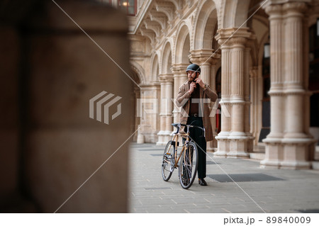Young businessman is putting on helmet before bicycle ride.Travel to work. Safety and eco friendly transport 89840009