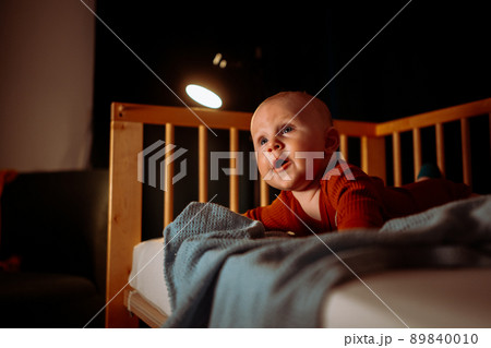 Adorable toddler baby boy with blue eye. crawling on his stomach at night  89840010