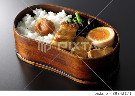 曲げわっぱに黒豆やほうれん草、半熟卵が入っている角煮弁当を黒背景で撮影 89842171