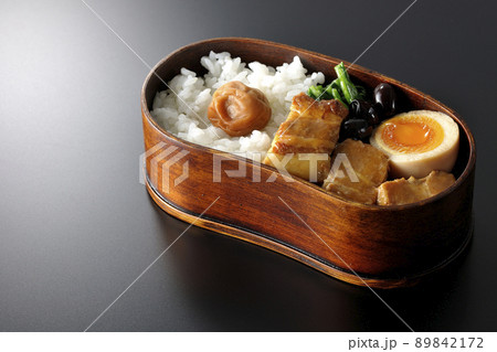 曲げわっぱに黒豆やほうれん草、半熟卵が入っている角煮弁当を黒背景で撮影 89842172
