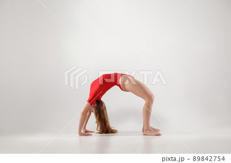 sporty woman balancing on hands and knees and holding back in form of arch while doing bridge urdhva dhanurasana yoga pose. indoor, light gray background. healthy lifestyle and leisure activity. sporty woman balancing on hands and knees and holding back in form of arch while doing bridge urdhva dhanurasana yoga pose. indoor, light gray background. healthy lifestyle and leisure activity. 89842754
