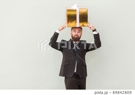 Dreaming or idea concept. Thoughtful businessman dreams and holding box on a head. Indoor shot 89842809