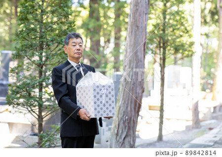 お墓で納骨式をする喪服の男性（骨壺） 89842814