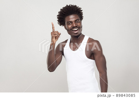 Good idea! Afro man finger up and toothy smiling. Indoor shot, gray wall Good idea! Afro man finger up and toothy smiling. Indoor shot, gray wall 89843085