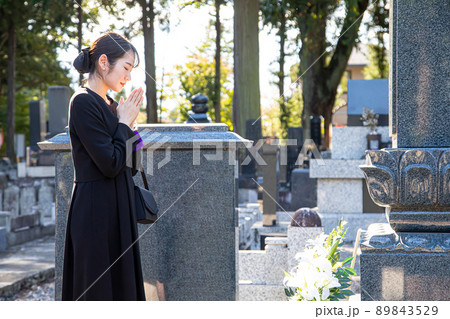 納骨式・お墓参りをする遺族の女性（合掌） 89843529