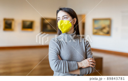 Woman tourist in protective mask admiring artworks at paintings exposition 89843781