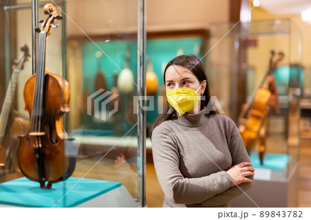 Brunette in protective mask visiting exhibition of medieval musical instruments 89843782