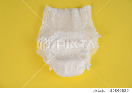 Adult diaper on a yellow background. Incontinence problems. 89846629