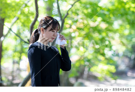 お葬式でハンカチを持って泣く女性 89848482