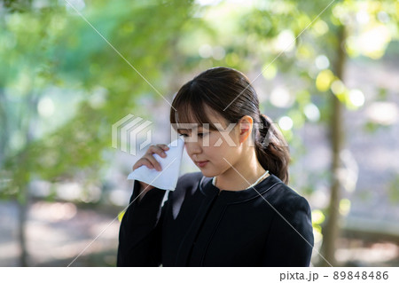 お葬式でハンカチを持って泣く女性 89848486