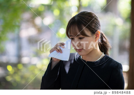 お葬式でハンカチを持って泣く女性 89848488