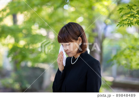 お葬式でハンカチを持って泣く女性 89848489